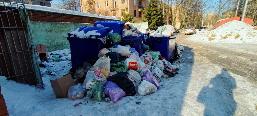 Переполненный мусорный контейнер на улице зимой