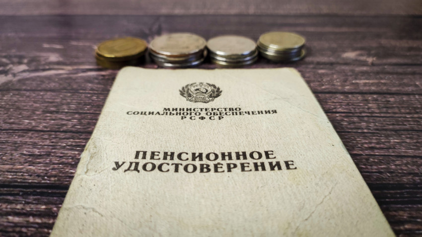 Пенсионное удостоверение и монеты российских рублей на деревянном столе