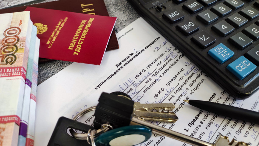 Договор купли-продажи недвижимости, окруженный деньгами, паспортом, пенсионным удостоверением, калькулятором и ключами