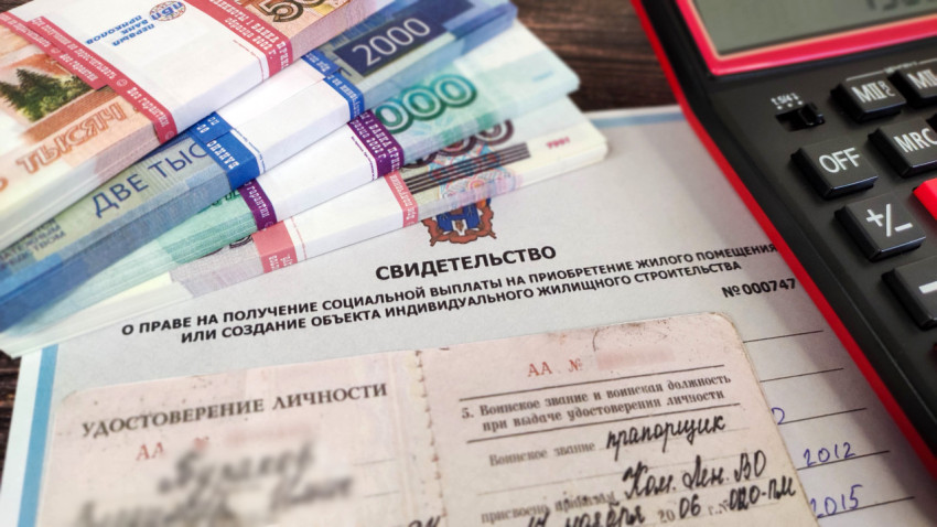 Жилищный сертификат, удостоверение личности военного, калькулятор и деньги на столе