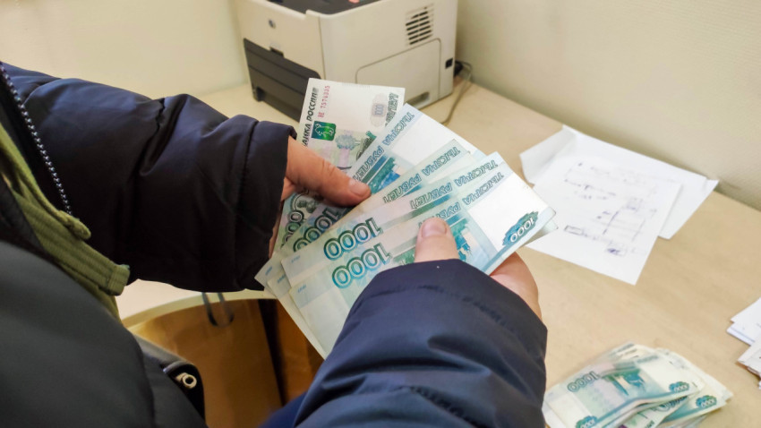 Человек пересчитывает наличные рубли в офисе