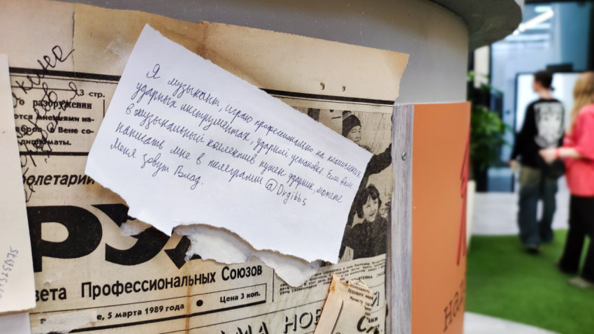 Рукописная записка на газетном фоне стенда
