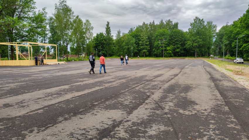 Новая парковка для автомобилей, окруженная зелеными деревьями