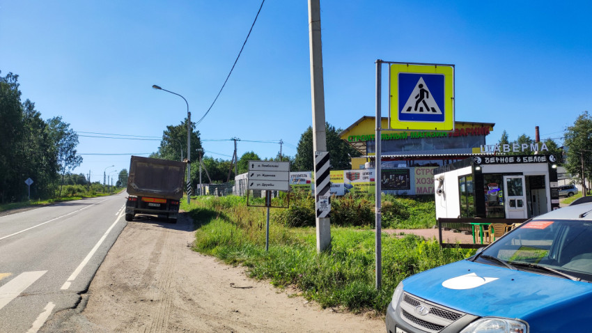 Дорога с грузовиком на обочине, дорожные знаки и здание строительного магазина