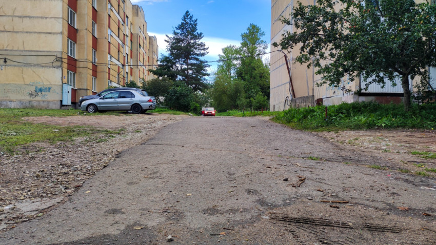Дорога во дворе жилого комплекса с проезжающим автомобилем