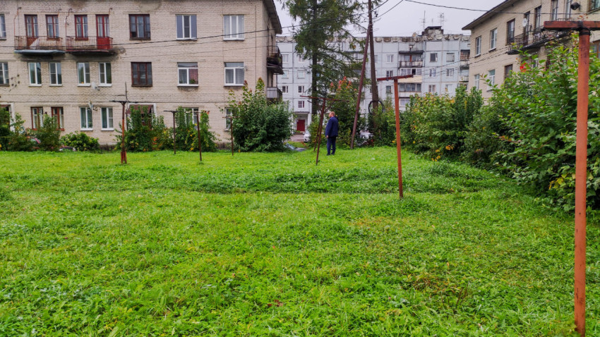Жилой двор с зелёной лужайкой и металлическими столбами