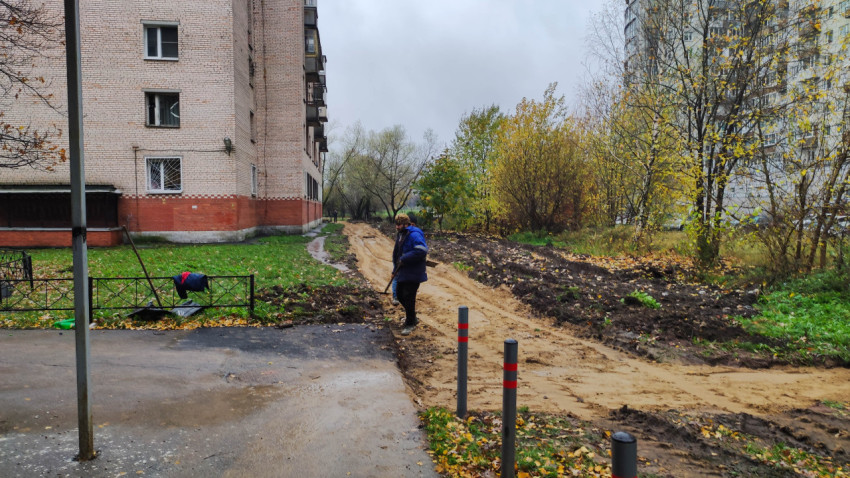 Подготовка основания для новой пешеходной дорожки возле жилого дома в осенний период