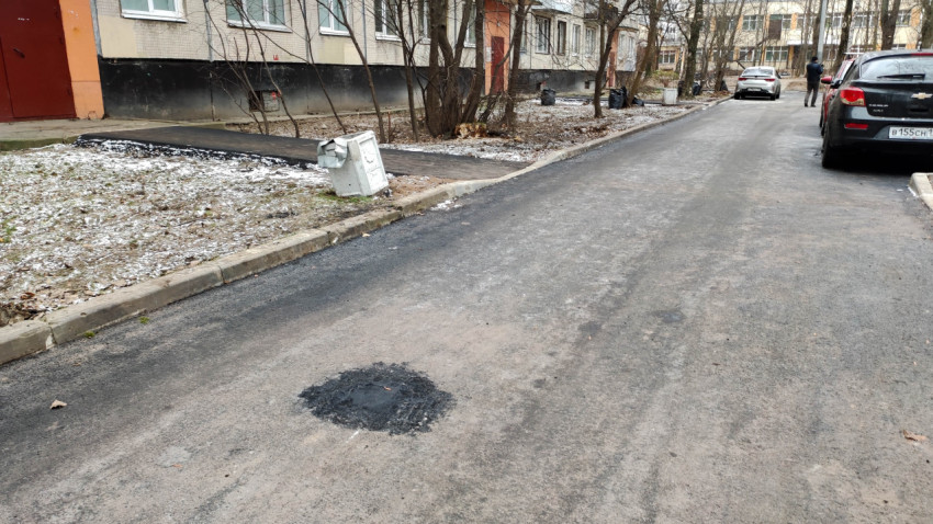 Дворовая дорога с ямочным ремонтом и мусорным контейнером