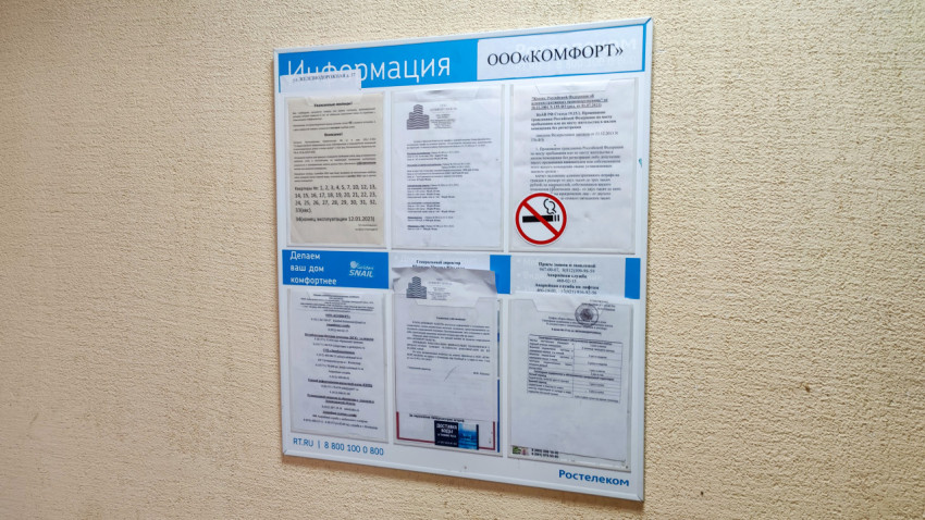 Информационный стенд с объявлениями управляющей компании в подъезде