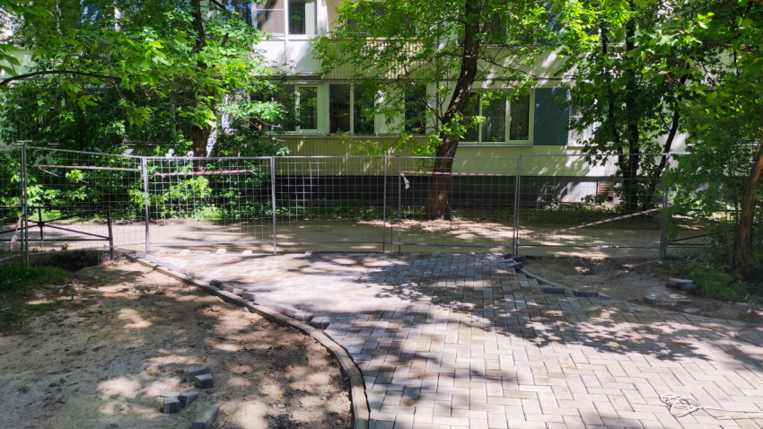 Участок двора с новой плиточной дорожкой за ограждением