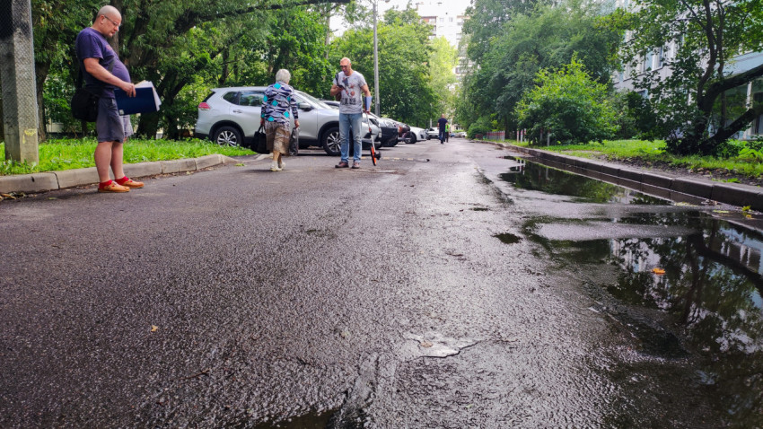 Дорога во дворе с людьми и лужами после дождя