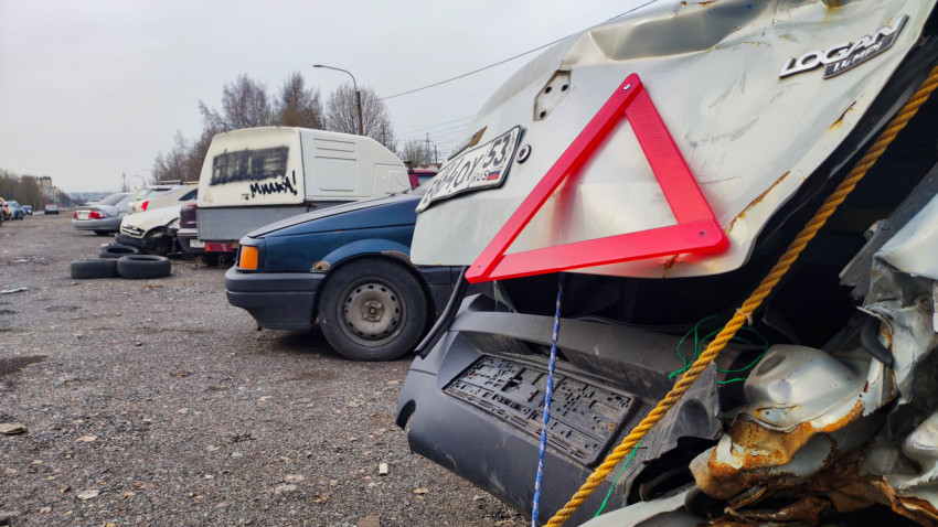 Повреждённый Renault Logan с аварийным знаком на стоянке