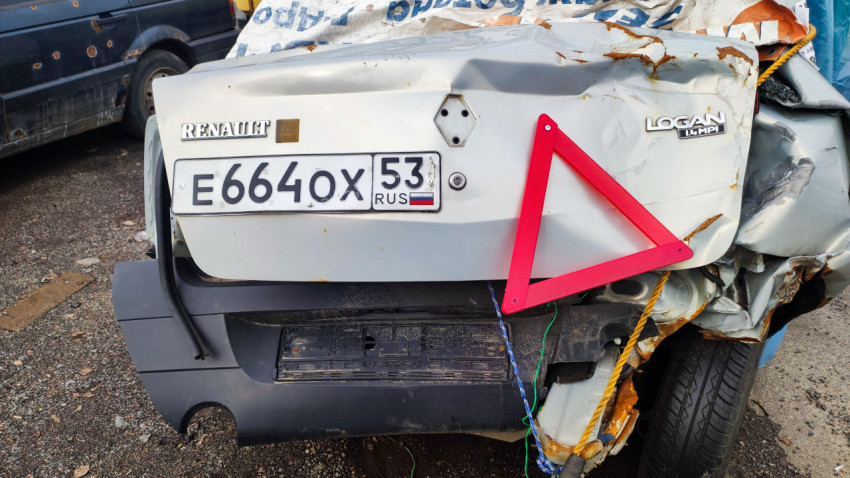 Повреждённый Renault Logan с регистрационным номером и аварийным треугольником