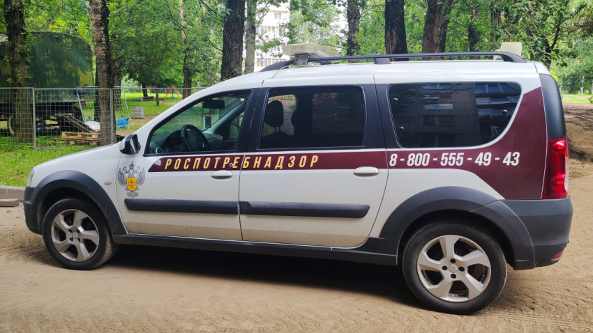 Боковой вид автомобиля Роспотребнадзора с контактным телефоном на борту в парковой зоне