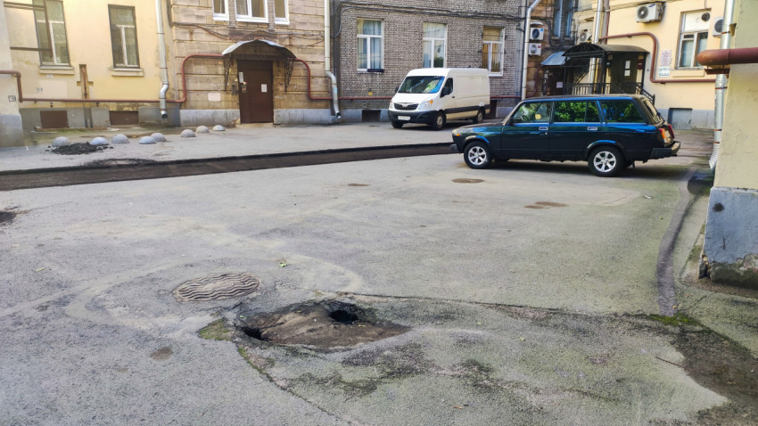 Двор с припаркованными автомобилями и провалом асфальта рядом с люком