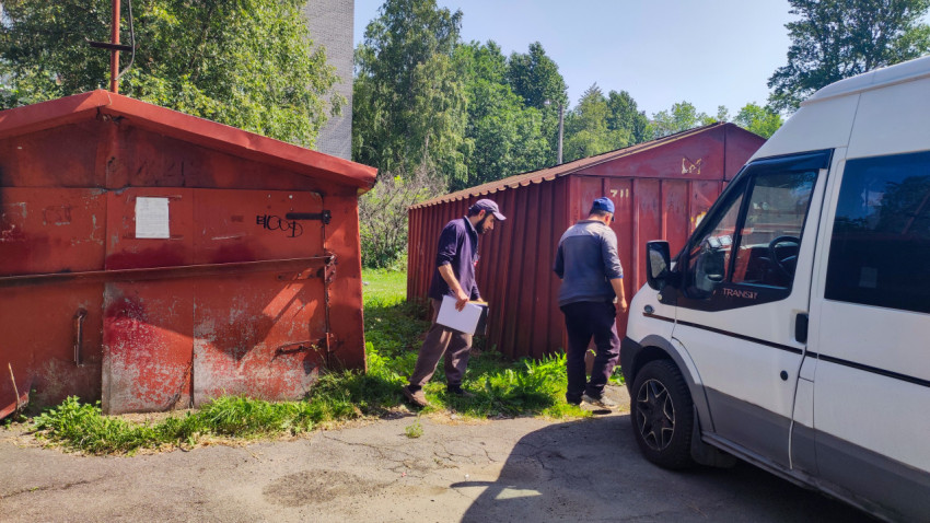 Двое рабочих осматривают металлические гаражи рядом с припаркованным фургоном