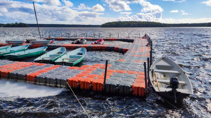 Ряд пластиковых лодок у понтонного причала и моторная лодка на швартовах