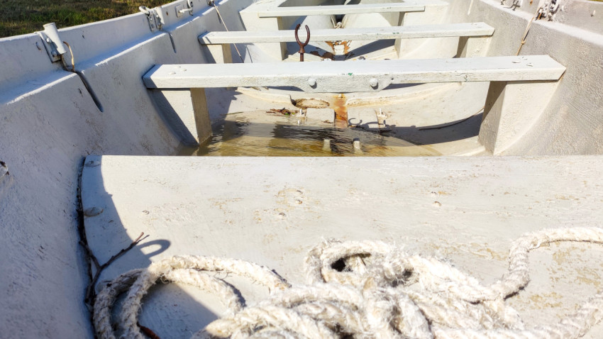 Внутри лодки видны банки, ржавые потёки и вода, собравшаяся на днище