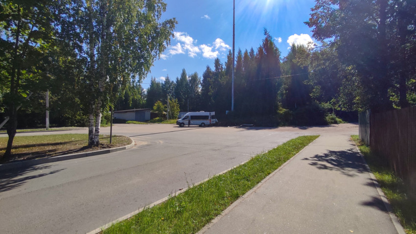 Спокойная улица в частном секторе с поворотом, тротуаром и припаркованным микроавтобусом