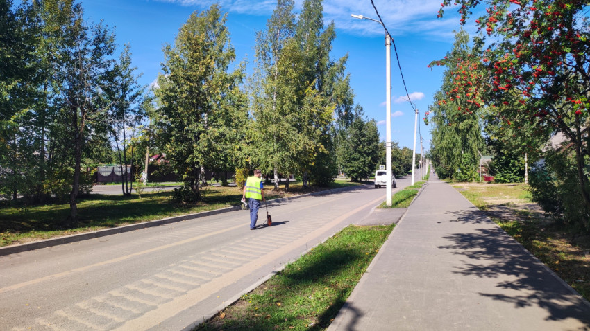 Измерение расстояния на улице: сотрудник катит измерительное колесо вдоль дороги с шумовой разметкой