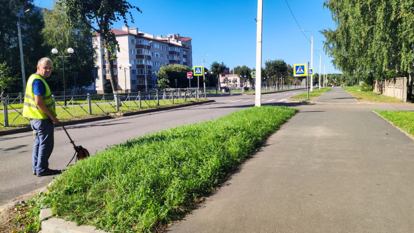 Мужчина в жилете мерным колесом размечает и измеряет участок у перекрёстка