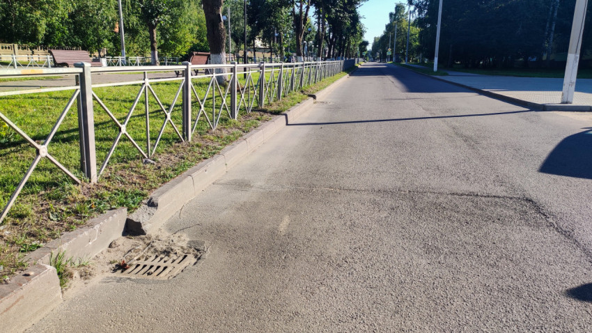 Ливнёвка у бордюра и заплатки на асфальте рядом с ограждением