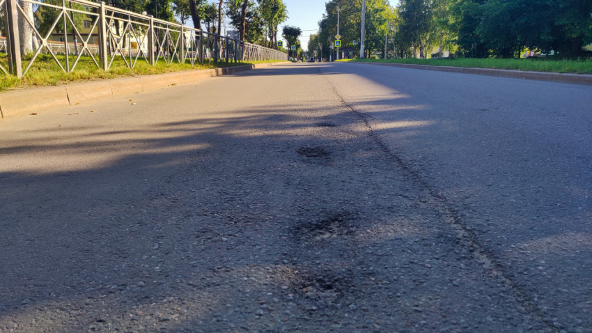 На дороге видно изношенное место: шов, заплатки и несколько выбоин в перспективе