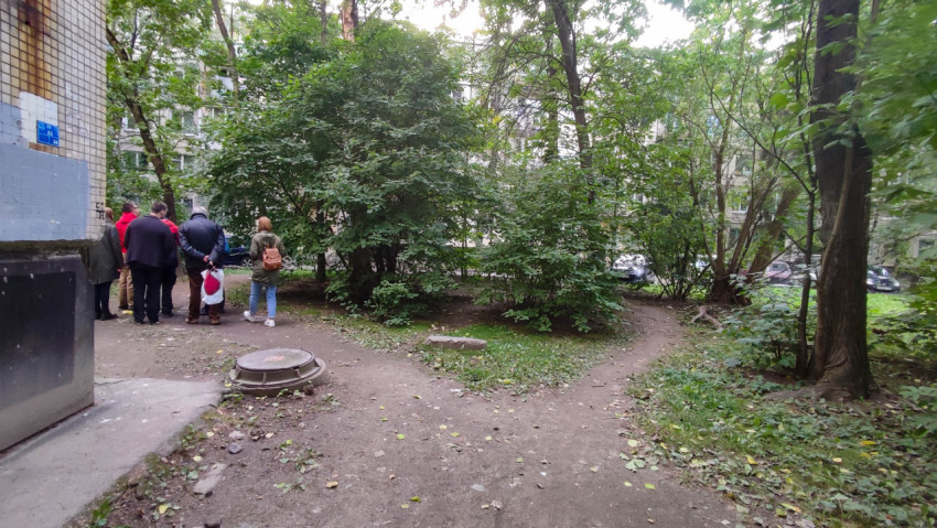 Группа людей в зелёной зоне возле жилого дома