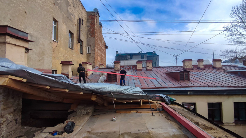 Рабочие проводят ремонт крыши старого здания в историческом районе