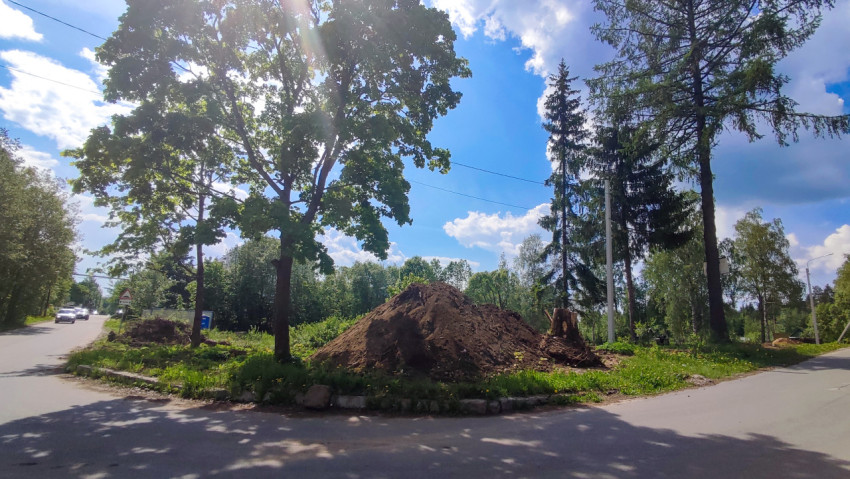 Участок дороги возле насыпи грунта и деревьев