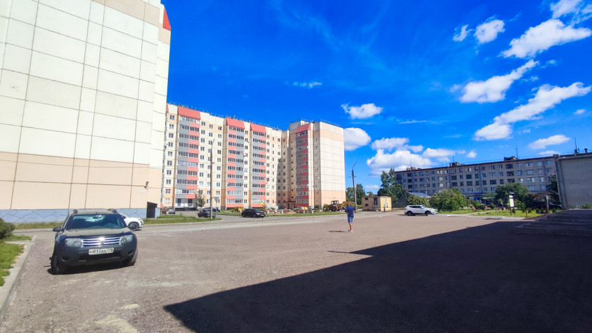 Пустая площадка и парковка у многоэтажных домов в солнечную погоду