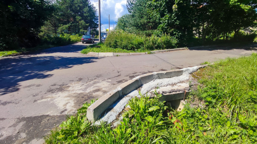 Перекрёсток дворовых проездов с повреждённым бордюром и водоотводным лотком