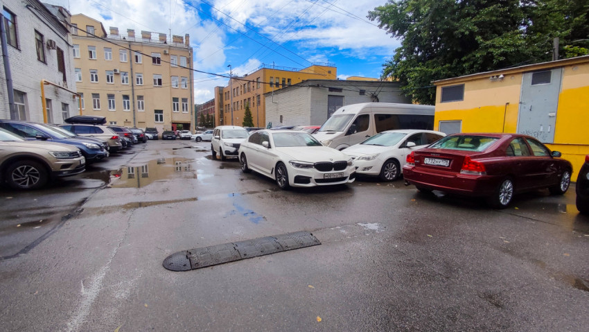 Дворовая парковка с лужами между городскими зданиями после дождя