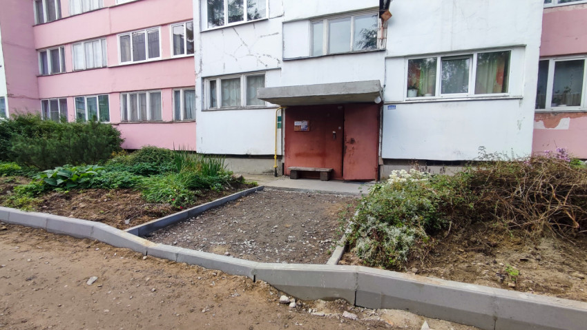 Подъезд панельного дома и новый бордюр, формирующий дорожку к входу во время благоустройства
