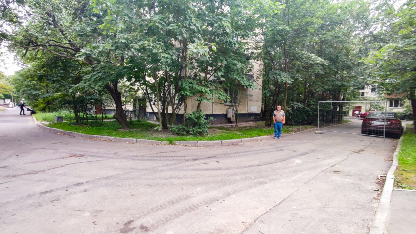 Перекрёсток дворовых проездов с заплатками асфальта и жильцами у зелёной зоны