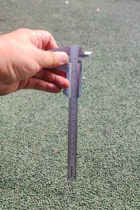 Макро штангенциркуля над резиновым покрытием с акцентом на рамку и направляющую